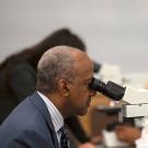 Chancellor Gary S. May looks into a microscope.