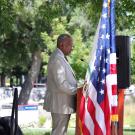 Chancellor Gary S. May speaks on stage next to American flag