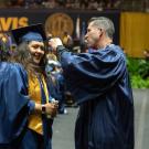 Person helps adjust graduation cap on student