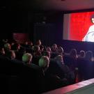 Insidea dark theater, on screen someone plays a banjo