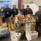 People pose for photo next to food collected for a food drive