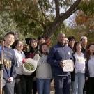 Chancellor Gary S. May poses for photo with group of students at garden cleanup event.