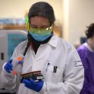 Woman holds tray of COVID-19 test samples.
