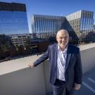George Baxter poses for photo with Aggie Square buildings in background.