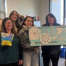 Group of people smile, wave and hold up bag of Tide Pods.