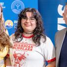 Two women and a man stand shoulder to shoulder