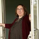 Katie Healey holds open a glass door to a building.