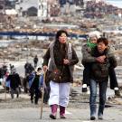 Women help each other leave the flattened city of Tohuku, Japan the day after a 9.0 earthquake on March 11, 2011 triggered a tsunami and nuclear meltdown, killing thousands.