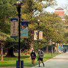 Two people walking on Centennial Walk, near the Quad.