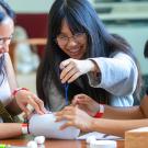Three students work with cotton balls, a plastic container and string in the annual Engineering Dean's Undergraduate Challenge 