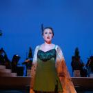 Woman on theatre stage, in costume, with blue-lighted background