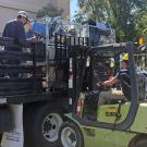 Items in metal containers are loaded onto a truck, by forklift.