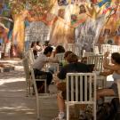Students studying on UC Davis campus on white tables and chairs in front of mural