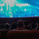 Chancellor Gary S. May, back to camera, watches movie in theater