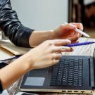Closeup of two people pointing at laptop screen