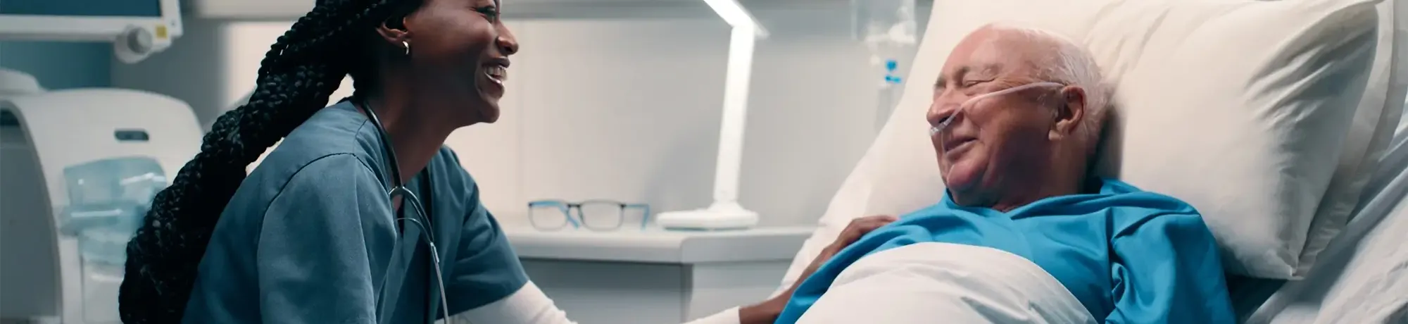 A doctor or nurse caring for a patient who is lying in bed in a hospital room