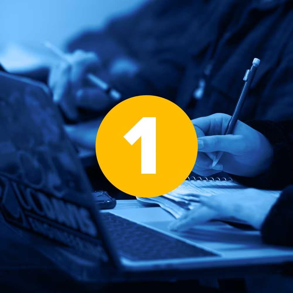 Student taking notes next to laptop