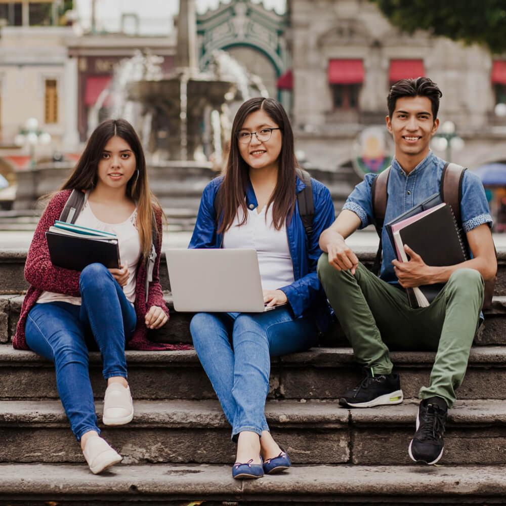 three students sitting on steps in front of some historic sites