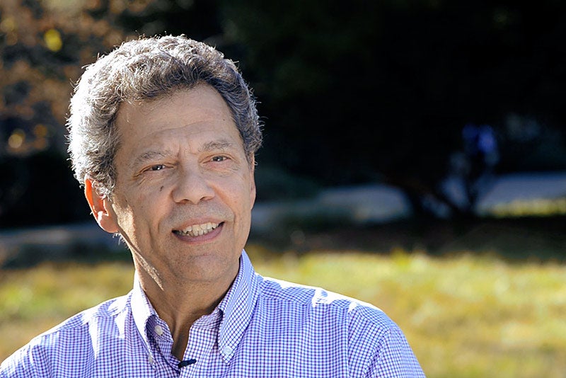 Head shot of Isaac Pessah in foreground with greenery behind