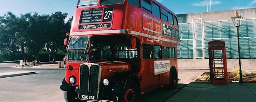 Red double decker bus parked next to a red telephone booth