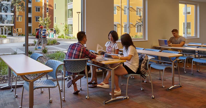Small group of students talking in lounge with large windows