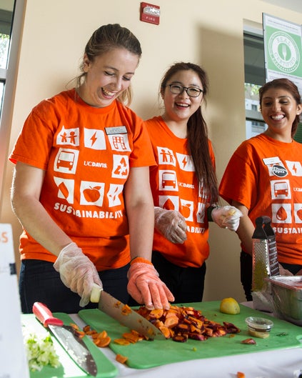 A student chops vegetables as two others look on