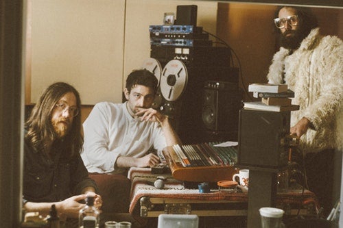 A 1970's vintage looking photo of the band in a recording studio.